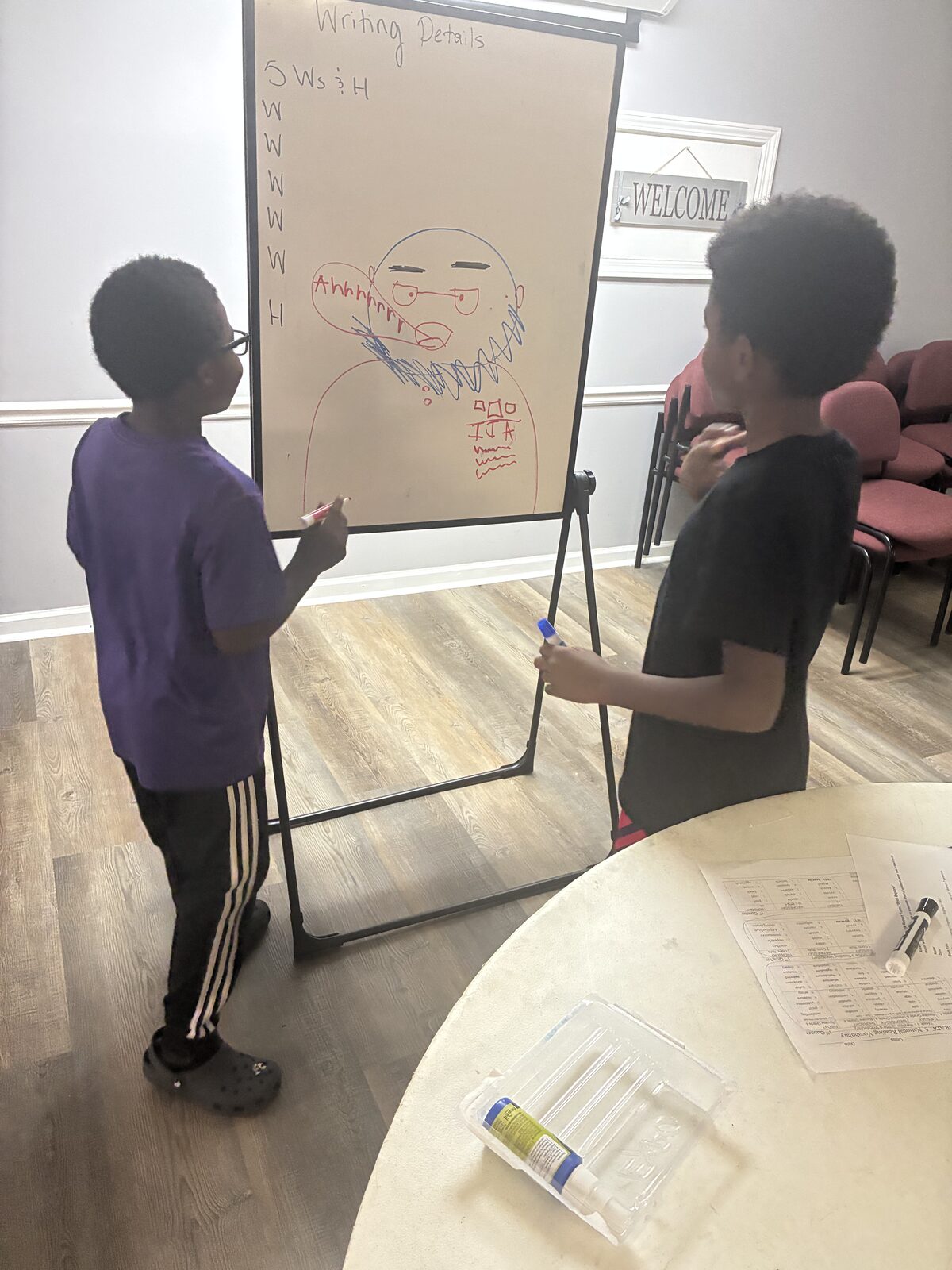 Two IIA students building a writing-details lesson together at the easel